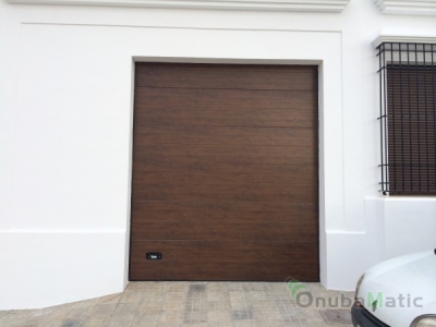 Puerta seccional automática en madera nogal  en vivienda unifamiliar en Moguer